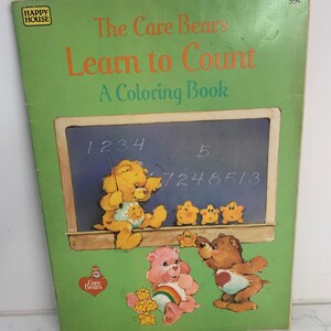 May include: A green colouring book featuring the Care Bears. The cover shows the Care Bears learning to count with a chalkboard and numbers. The title is "The Care Bears Learn to Count: A Colouring Book".