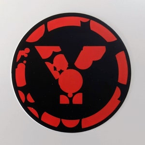 May include: A red and black circular sticker with a stylized letter Y formed from smaller red shapes.