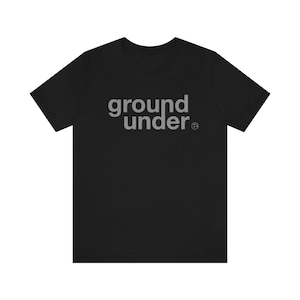 May include: Black t-shirt with the text "ground under" in white lettering.