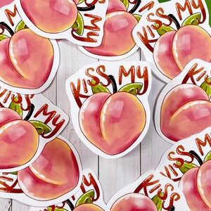 May include: A set of 10 peach-coloured stickers with the text "Kiss My" and a peach graphic. The stickers are arranged in a circle.