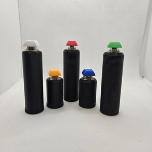 Op de afbeelding: Zes zwarte cilindrische voorwerpen met verschillende gekleurde toppen. De toppen zijn wit, rood, groen, geel, blauw en wit. De voorwerpen zijn in een rij op een wit oppervlak gerangschikt.