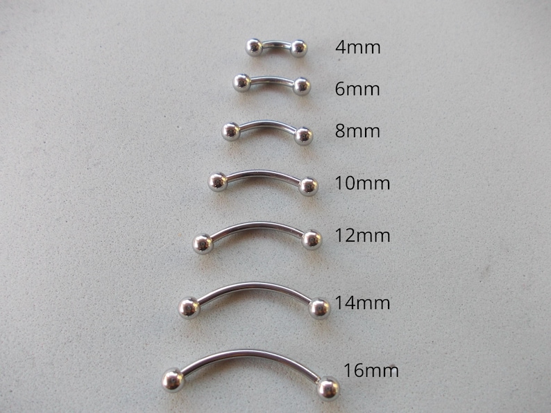 May include: A collection of curved barbell body jewelry in various sizes, ranging from 4mm to 16mm. Each piece is silver-colored with a curved bar and two small, round balls at the ends. The sizes are labeled in millimeters.