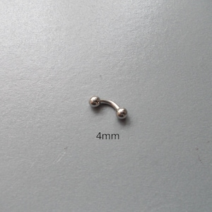 May include: A curved, silver-colored eyebrow piercing with two small, round balls at each end. The text "4mm" is printed below the piercing, indicating its size. The jewelry is set against a gray background.