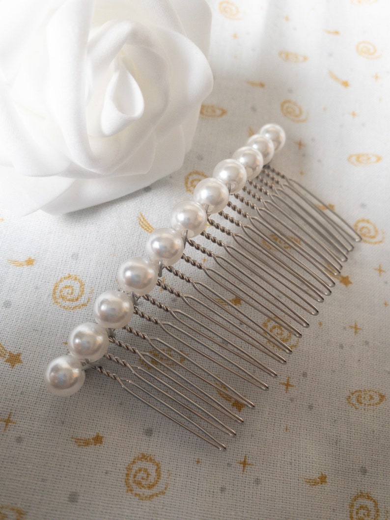 May include: A silver hair comb with a row of white pearl beads.