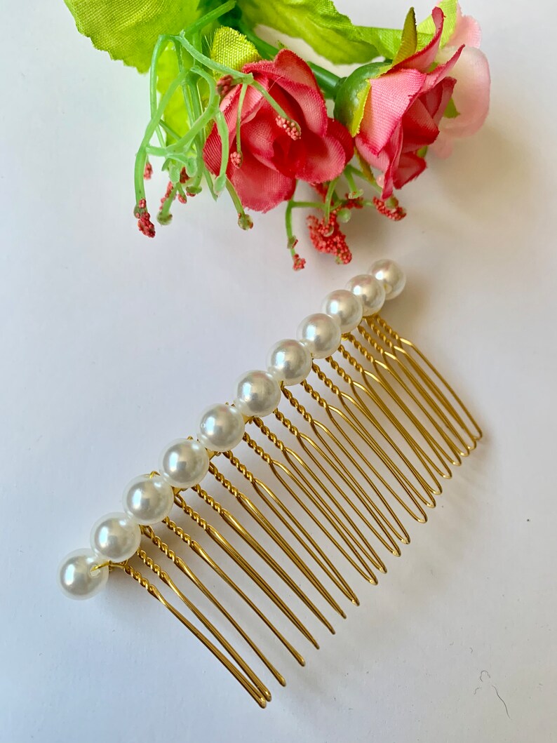 May include: A gold hair comb with a row of white pearl beads. The comb has a twisted design and is perfect for adding a touch of elegance to any hairstyle.