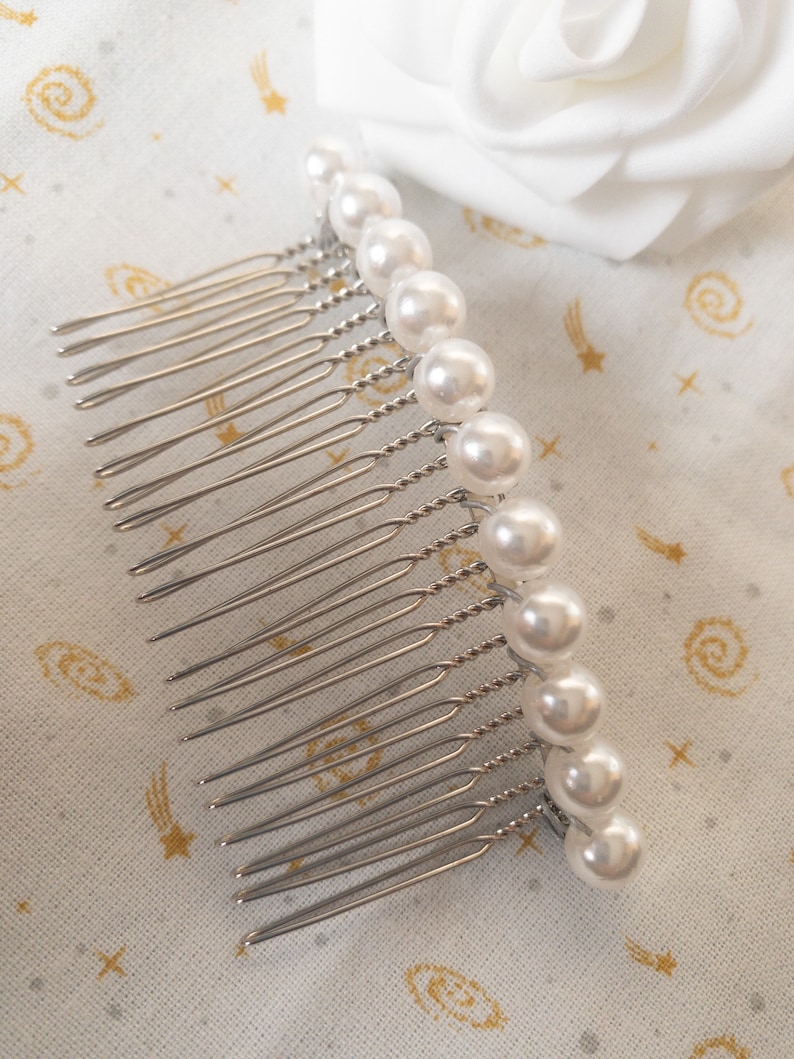 May include: A silver hair comb with a row of white pearl beads. The comb has a twisted wire design and is perfect for adding a touch of elegance to any hairstyle.