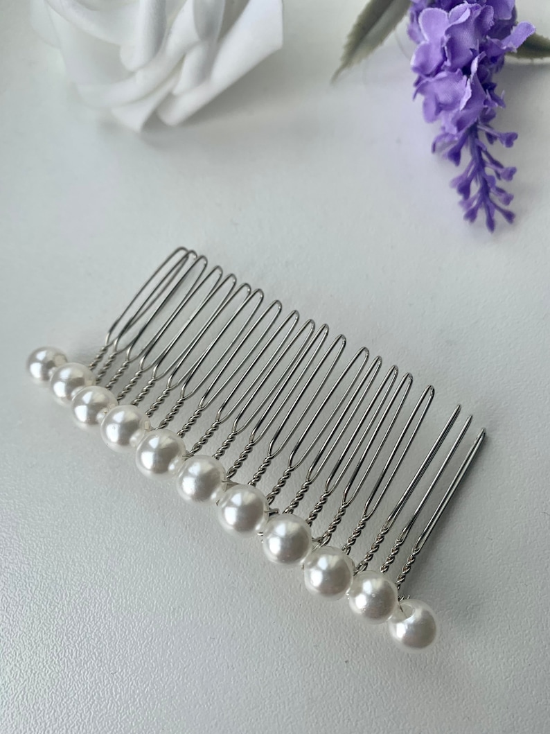 May include: A silver hair comb with a row of white pearl beads attached to the teeth.