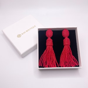 May include: A pair of red beaded tassel earrings in a white box with the text "Kay Boutique".