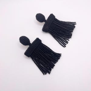 May include: A pair of black beaded tassel earrings. The earrings are made of small black beads and have a tassel design. The earrings are about 2 inches long.