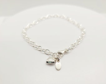 May include: A silver chain bracelet with a small heart charm and a tag that says "925".