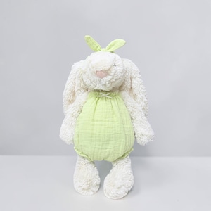 May include: A plush stuffed rabbit toy with cream-colored textured fur, long floppy ears, and a small pink nose. The rabbit is wearing a light lime green muslin romper with a gathered neckline and a small bow detail at the center of the chest.