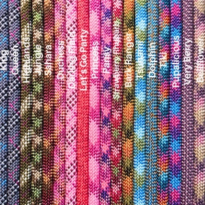 May include: A close-up of 20 different colorful paracord ropes with various patterns and names printed on each rope. The names include "Shadow", "Rainbow Road", "King", "Highlands", "Jungle", "Sahara", "Duchess", "Darling Plaid", "Let's Go Party", "Princess", "Pansy", "Strawberry Rhubarb", "Bark Ranger", "Tiki", "Pupalicious", "Very Berry", "Bellflower", "Flower Child", and "Fuzzy".
