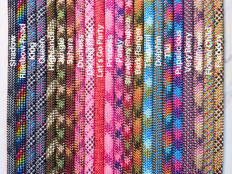 May include: A close-up of 20 different colorful paracord ropes with various patterns and names printed on each rope. The names include "Shadow", "Rainbow Road", "King", "Highlands", "Jungle", "Sahara", "Duchess", "Darling Plaid", "Let's Go Party", "Princess", "Pansy", "Strawberry Rhubarb", "Bark Ranger", "Tiki", "Pupalicious", "Very Berry", "Bellflower", "Flower Child", and "Fuzzy".