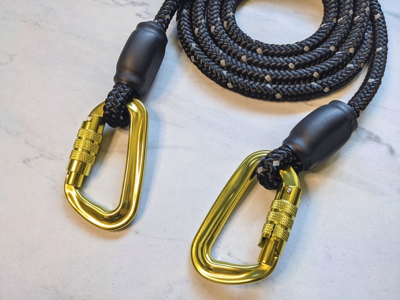 May include: Black rope dog leash with two gold metal clips. The leash is made of thick rope with black and white accents.