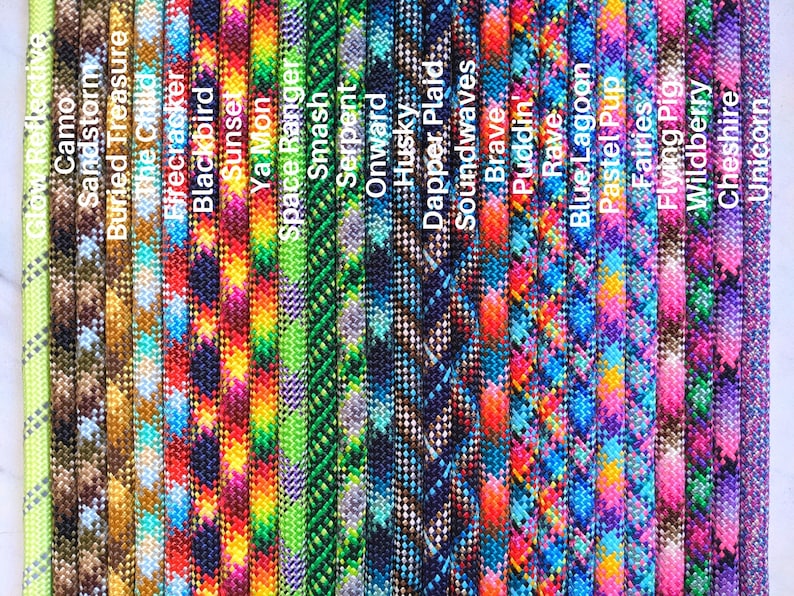 May include: A collection of 20 colorful paracord ropes with various patterns, including camouflage, floral, and geometric designs. The ropes are arranged vertically and labeled with names such as "Camo", "Sandstorm", "Buried Treasure", and "Firecracker".