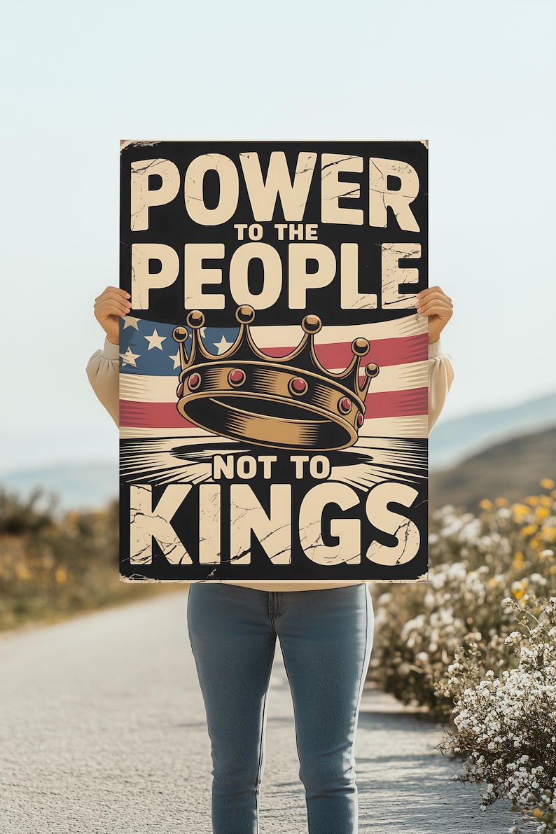 May include: A rectangular sign with the text "POWER TO THE PEOPLE NOT TO KINGS" in a distressed font. The sign features a crown over an American flag design. The sign is held by a person.
