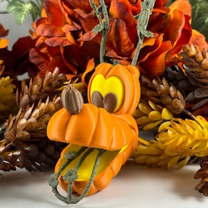May include: Orange pumpkin-shaped Halloween decoration with a cartoon face and green stem. The pumpkin is open and has a yellow interior.