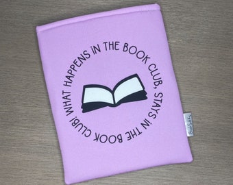 May include: A lavender book sleeve with the text "What happens in the book club, stays in the book club" in a circle around an open book illustration.
