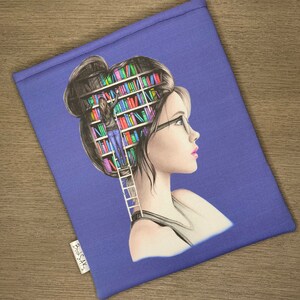 May include: A purple book sleeve featuring a colourful illustration of a person with a bookshelf inside their head. The person is looking to the right and wearing glasses. The text "Bookish" is printed on the sleeve.