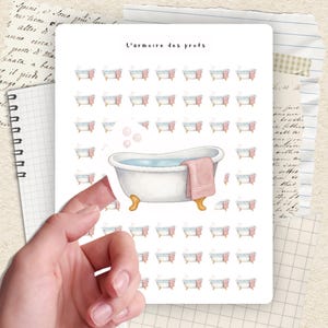 May include: A white ceramic mug with a black handle and the text "But First, Coffee" in a bold, black font. The mug is set against a blurred background, suggesting a cozy setting. The mug appears to be approximately 4 inches tall.