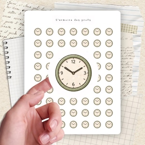 Peut inclure: Une planche d'autocollants avec un motif répété de petites horloges et une horloge plus grande au centre. Le texte "L'armoire des profs" est en haut. Les horloges ont une esthétique vintage avec un bord vert.