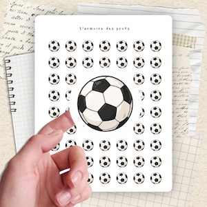 May include: A sheet of stickers featuring soccer balls. The stickers are white with black pentagons. The text "L'armoire des profs" is at the top. The sheet is on a background of lined paper and handwritten notes.