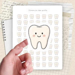 May include: A white sticker sheet featuring a large cartoon tooth with a smiling face and blush, surrounded by smaller smiling tooth illustrations. The text "L'armoire des profs" is at the top. The sticker sheet is held by a hand.