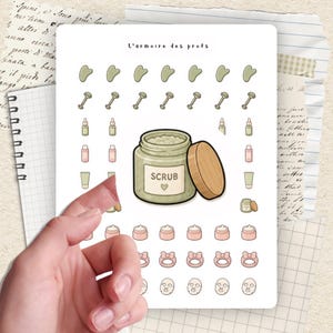 May include: A sheet of stickers featuring skincare products. The stickers include jade rollers, bottles, jars of scrub, face masks, and headbands. The text "L'armoire des profs" is at the top, and the word "SCRUB" is on a jar.