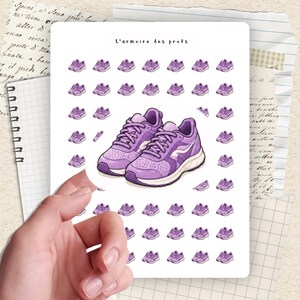 May include: A sticker sheet featuring a pair of purple sneakers and several smaller sneaker illustrations. The text "L'armoire des profs" is at the top. The sticker sheet is held by a hand.