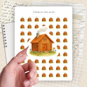 Peut inclure: Une planche d'autocollants avec une illustration d'une cabane en rondins détaillée, de la fumée s'échappant de la cheminée, entourée de petits autocollants de cabanes. Le texte "L'armoire des profs" est en haut.