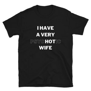 Puede incluir: Camiseta negra con texto blanco: "I HAVE A VERY PSYCHOTIC WIFE". El texto está centrado en la parte delantera. La camiseta tiene mangas cortas y cuello redondo. Prenda casual.