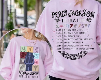 May include: Pink sweatshirt with a graphic of a trident and symbols from the Percy Jackson series. The text "Percy Jackson The Eras Tour" is printed on the front and back of the sweatshirt.