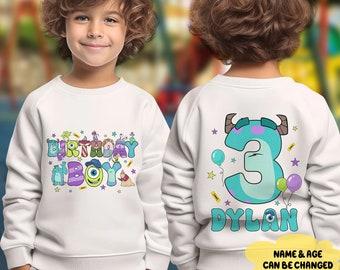 May include: White sweatshirt with colorful "BIRTHDAY BOY" text and cartoon characters on the front. The back features a large number "3" with a monster design, balloons, and the name "DYLAN". The text "NAME & AGE CAN BE CHANGED" is also visible.
