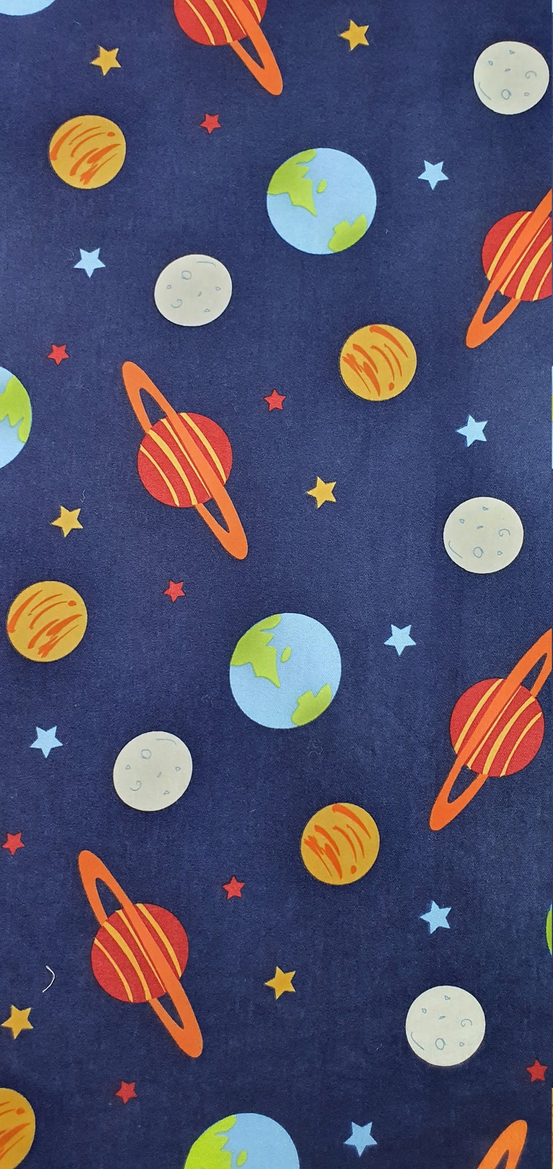 May include: A navy blue fabric with a repeating pattern of planets, stars, and moons. The planets are in various colors, including orange, red, and blue. The stars are yellow and white. The moons are gray.