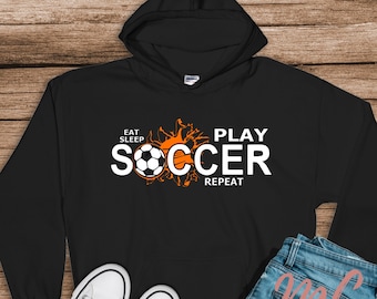 May include: Black hooded sweatshirt with an orange football graphic and the text "Eat Sleep Play Soccer Repeat".