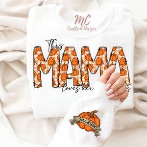 May include: White sweatshirt with the text "This Mama loves her" in black outlined font. The letters are filled with a pattern of orange pumpkins on a white and orange gingham background. A smaller white sweatshirt with a brown ribbon and the text "Jackson" is shown in the bottom right corner.
