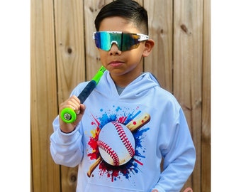 Può includere: Felpa bianca con una grafica di baseball colorata che presenta una palla da baseball, mazze e schizzi di vernice. La felpa ha un cappuccio con coulisse e una tasca a marsupio. Il testo "MC Crafts & Designs" è visibile nell'angolo in basso a destra dell'immagine.