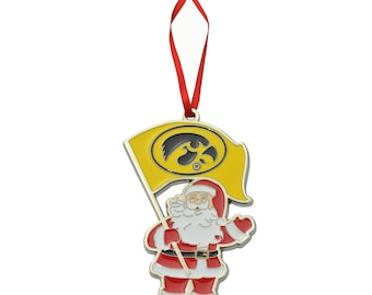 May include: A gold-colored Christmas ornament featuring a Santa Claus holding a yellow flag with a black hawk logo. The flag has the letters "IOWA" on it.