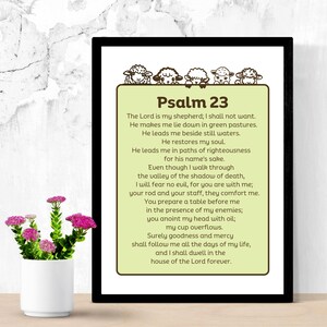 Op de afbeelding: Een printbare wandkunstprint met een groene achtergrond en bruine tekst. De tekst is Psalm 23, een passage uit de Bijbel. De print heeft een rand van bruine schapen.