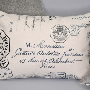 May include: A white pillow with a blue and black vintage postage stamp design. The pillow features a French address and the text "M. Monsieur Gustave Antoine Kerrean 93 Rue d'Alembert Paris".