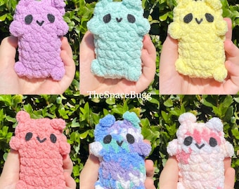 May include: Six crocheted plush toys in various pastel colors, including purple, blue, green, yellow, pink, and red. Each toy has a simple, smiling face with black eyes and a small mouth.