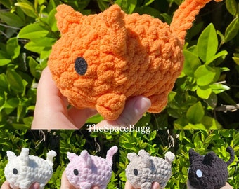 May include: A set of five crocheted plush toys in various colors, including orange, white, pink, gray, and black. Each toy has a single black eye and a unique shape.