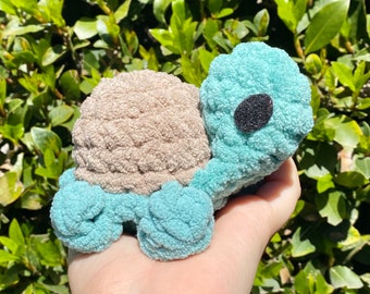 May include: A crocheted turtle toy with a light blue body and a brown shell. The turtle has a black eye.