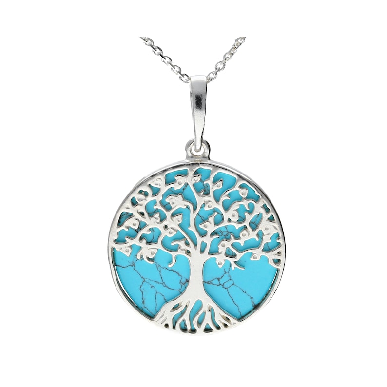 Op de afbeelding: Een zilveren ketting met een turquoise boom des levens hanger. De hanger is rond en heeft een gedetailleerd boomontwerp met ingewikkelde takken en bladeren.