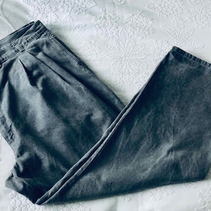 May include: A pair of grey pleated trousers with a relaxed fit. The trousers are made from a soft, comfortable fabric and have a casual look.