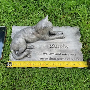 K&ouml;nnte beinhalten: Eine graue Gedenktafel aus Beton mit einer geformten Katzenfigur. Die Tafel tr&auml;gt die Aufschrift "Murphy We love and miss you more than words can say".