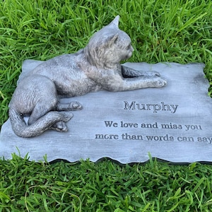 K&ouml;nnte beinhalten: Ein graues Beton-Katzen-Denkmal mit der Inschrift "Murphy We love and miss you more than words can say"