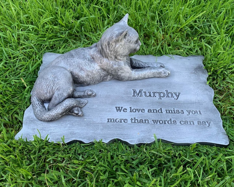 K&ouml;nnte beinhalten: Ein graues Beton-Katzen-Denkmal mit der Inschrift "Murphy We love and miss you more than words can say"