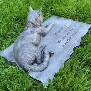 K&ouml;nnte beinhalten: Ein graues Beton-Katzen-Denkmal mit der Inschrift "Murphy. We love and miss you more than words can say."