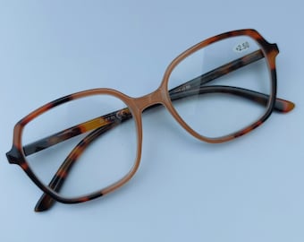 Könnte beinhalten: Lesebrille aus Schildpatt mit quadratischem Gestell und klaren Gläsern. Die Brille hat eine +2,50-Vergrößerung.